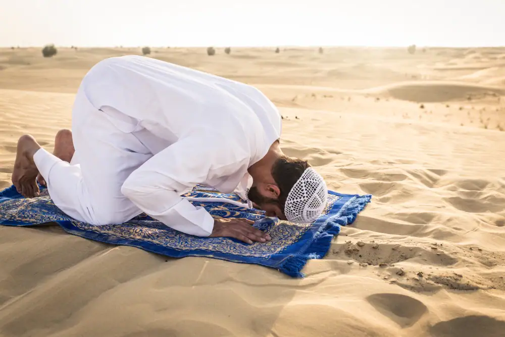 رجل يصلي في الصحراء بجانب سيارته