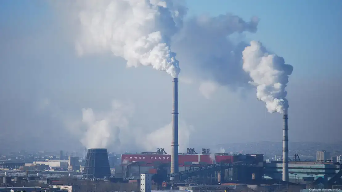 منظر لمصنع يطلق الدخان في الهواء وبحيرة ملوثة