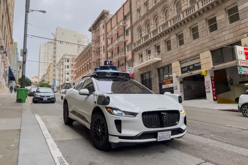 سيارة أجرة روبوتية من Waymo تسير في شارع مدينة بدون سائق