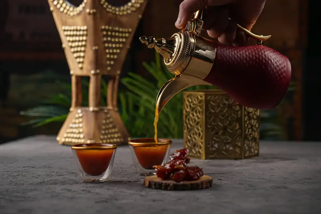 فنجان من القهوة العربية التقليدية بجانب طبق من التمر السكري