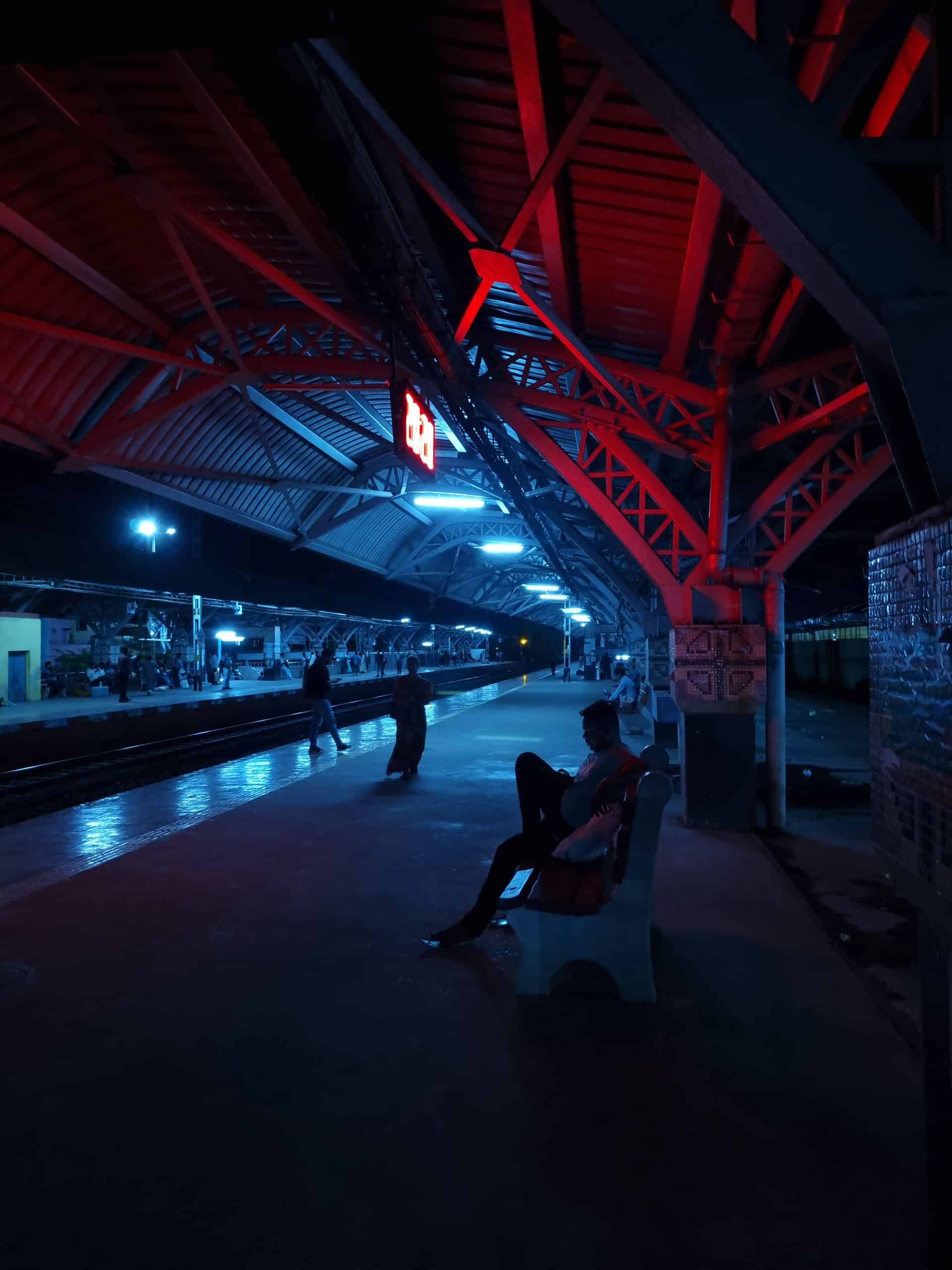 A captivating night view of an Indian train station with striking red and blue lighting.